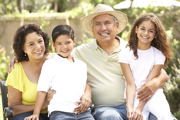 senior citizen male and female sitting on bench holding young male and female children