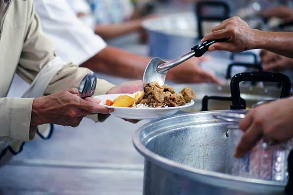 a person spoons food onto a plate