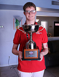 a teenage girl holding up a large trophy