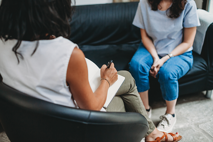 two women sit across from each other on sofas