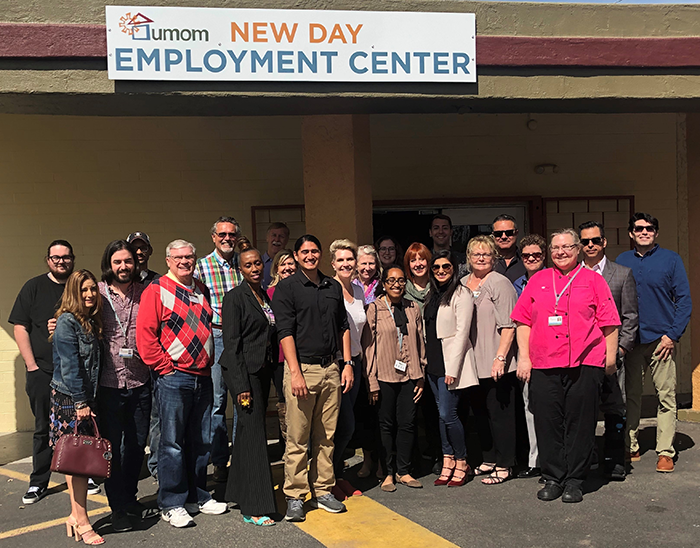 a group of people stand in front a building with a sign that reads "UMOM New Day Employment Center"