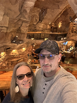 A couple takes a selfie in a cave-like environment with rock formations.