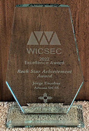 an award made of glass reads "WICSEC 2022 Excellence Award, Rock Star Achievement Award, Jorge Escobar, Arizona DCSS"