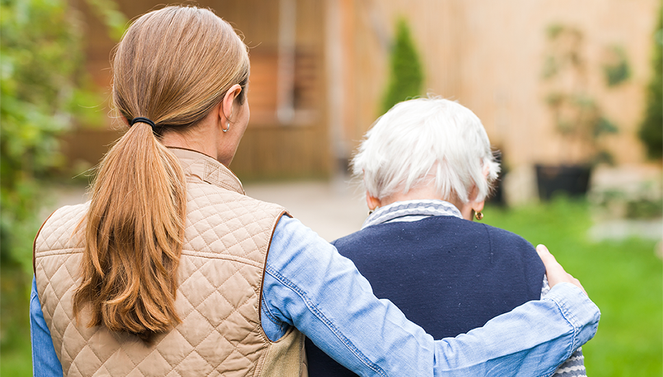 The view from behind a woman who has her arm around an older adult