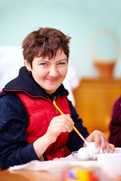 Woman holding a paint brush and smiling at the camera.