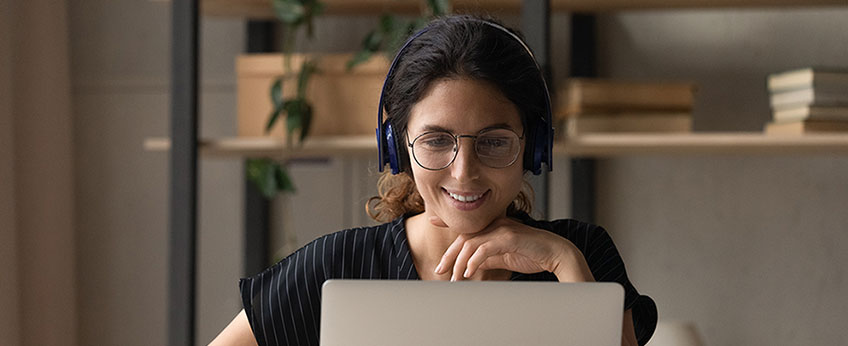 woman wearing a headphones works on a laptop computer