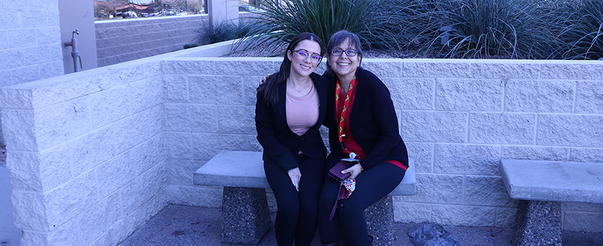 Two women sit outside the entrance to their place of employment