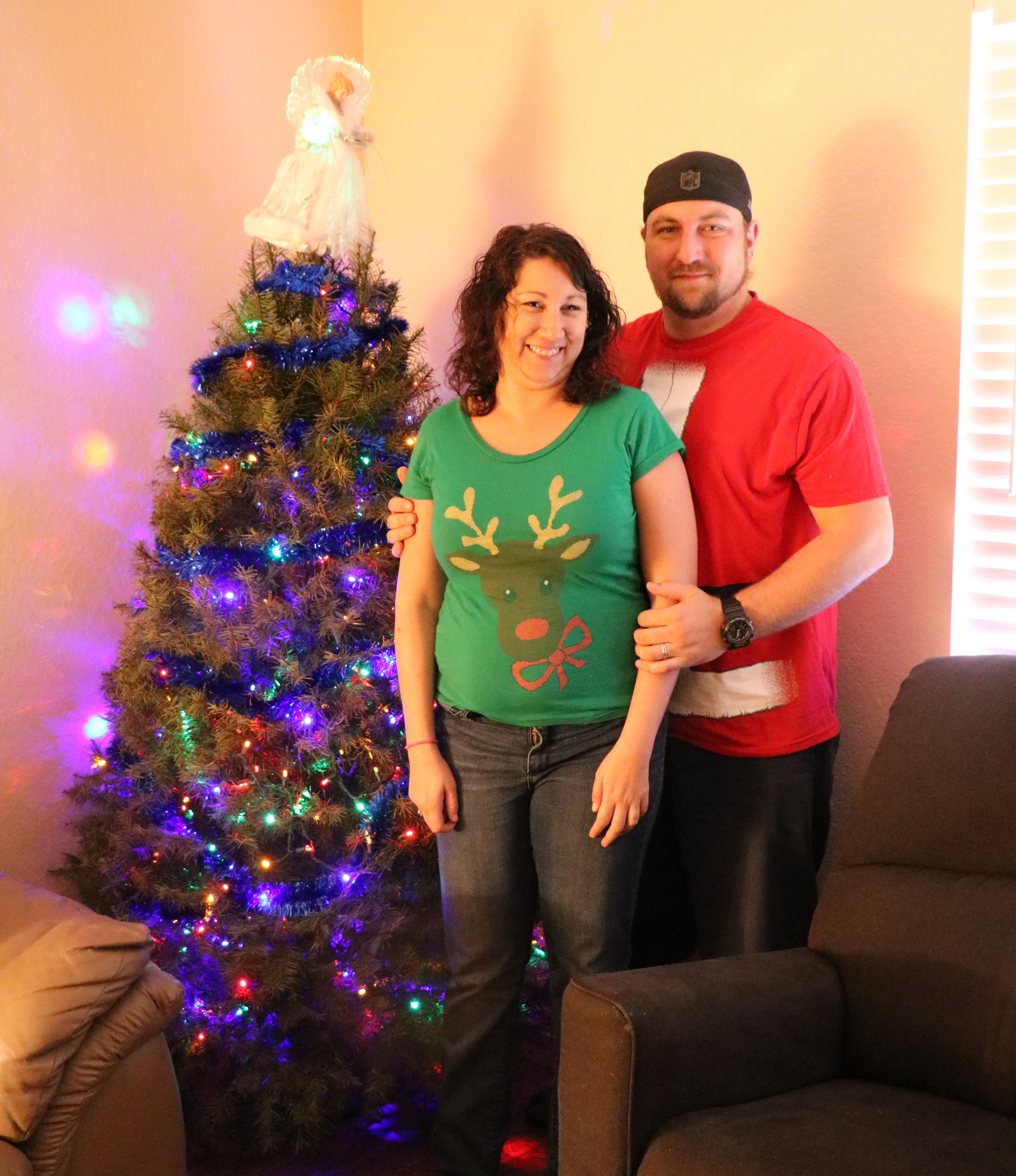 Young couple pose for a photo by their decorated Christmas tree