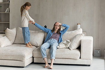 young girl trying to pull mother up from the sofa