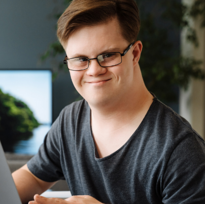 Young man at a computer smiling for the camera.