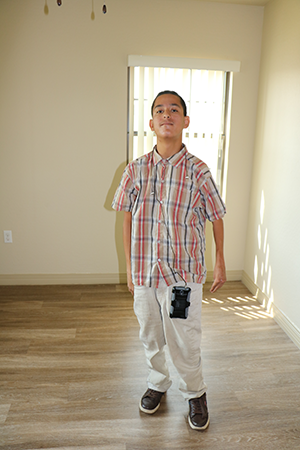 Young man stands in the center of an empty room that he selected as his new bedroom.