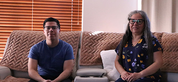 a young man sitting on livingroom sofa next to his mother