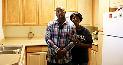 Man with his mother standing in the kitchen of their apartment home.