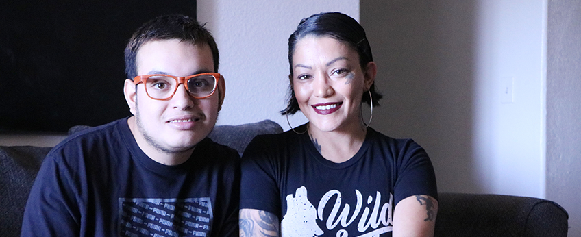 a young man wearing red glasses sits on a sofa, next to a woman