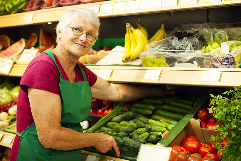 an older woman working in the produce section of a grocery store