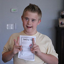 Teenage boy holds up a spelling test with a perfect grade