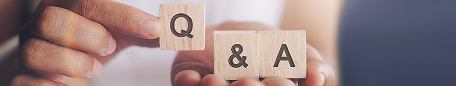 a hand holds wooden squares with the letters Q and A