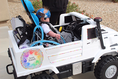 side view of toddler behind wheel of toy car