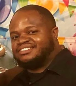 A Black male with brown eyes, black hair, mustache and beard.
