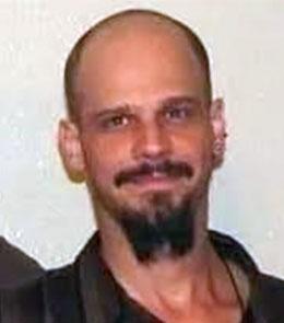 A White male with brown eyes, brown hair, with a mustache and beard.