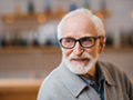 An older man sitting down and smiling