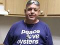 a man wearing a purple t-shirt that reads "peace love oysters"