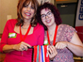 Two women smiling and holding several award medals.