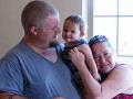 a family - dad, 10-month-old daughter and mom - snuggle together