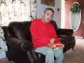 Man sitting on couch holding stuffed reindeer toy.