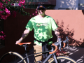 Man wearing sunglasses and a ball cap stands with his bicycle out on his enclosed patio
