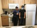 Mother and adult son stand next to the refrigerator in the kitchen of their new apartment home.