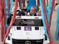 Toddler drives an adapted toy vehicle through a pretend car wash.