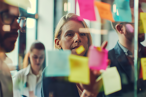 Business Team Looking at Sticky Notes Posted on Glass Wall
