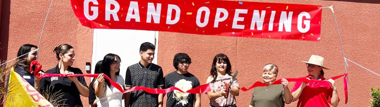 a group of people holding a banner that reads "Grand Opening"