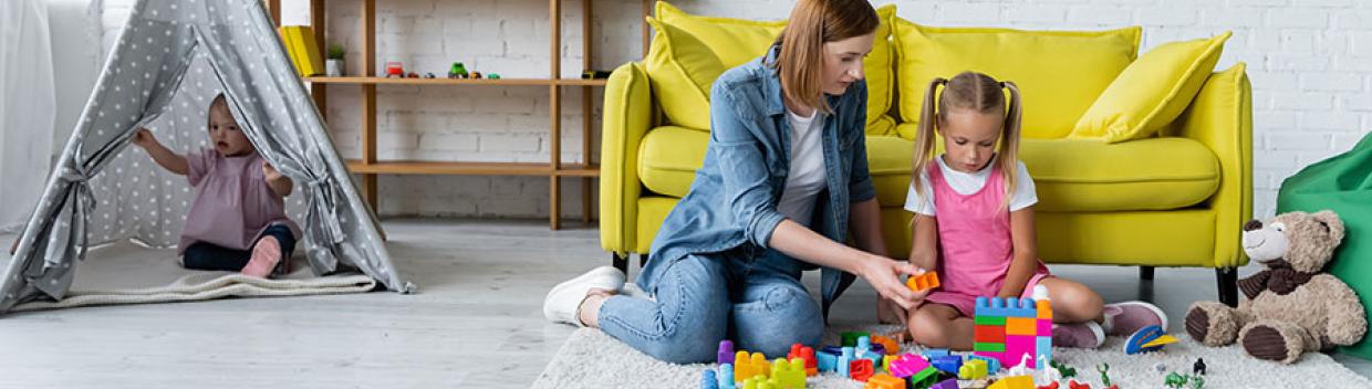 woman and little girl playing with colorful building blocks