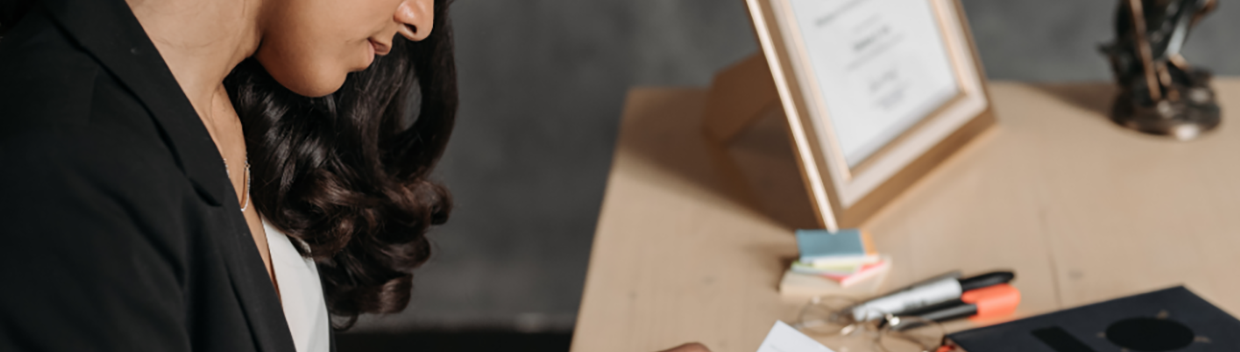 A woman looks at paperwork in front of a desk.