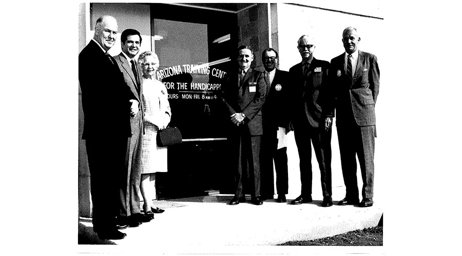 a group of business professionals stand in front of a building