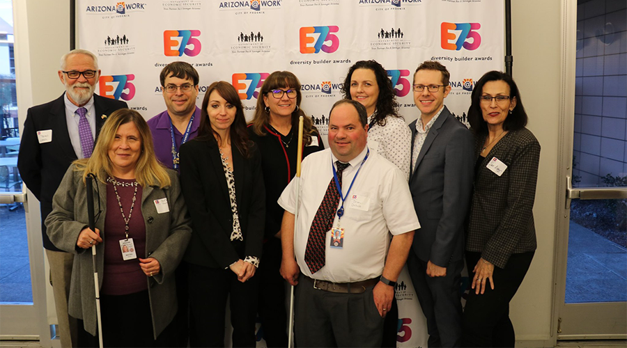 a group of business professionals stand before a backdrop that reads E75