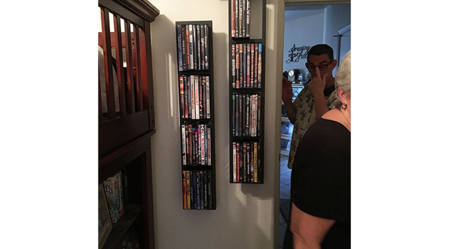 a variety of movie cases are neatly stored on two wall cabinets