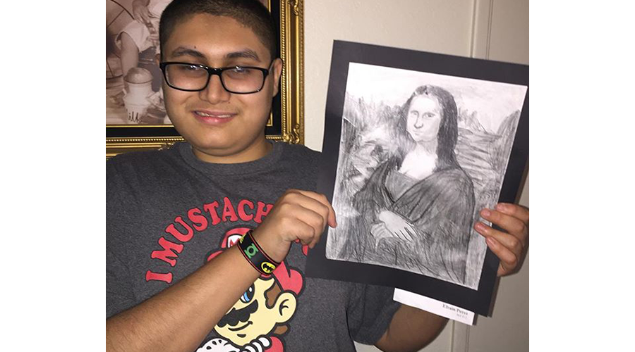 a teenage boy smiles; he is holding up a drawing of the Mona Lisa