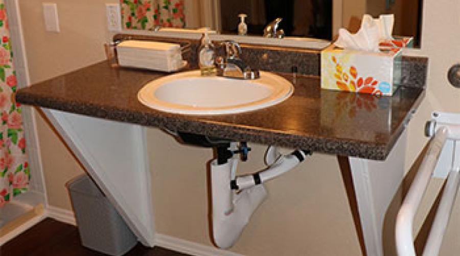 A bathroom sink in front of a mirror, without cabinets underneath so it is more accessible.