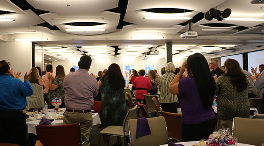 People in hall standing at their tables and applauding