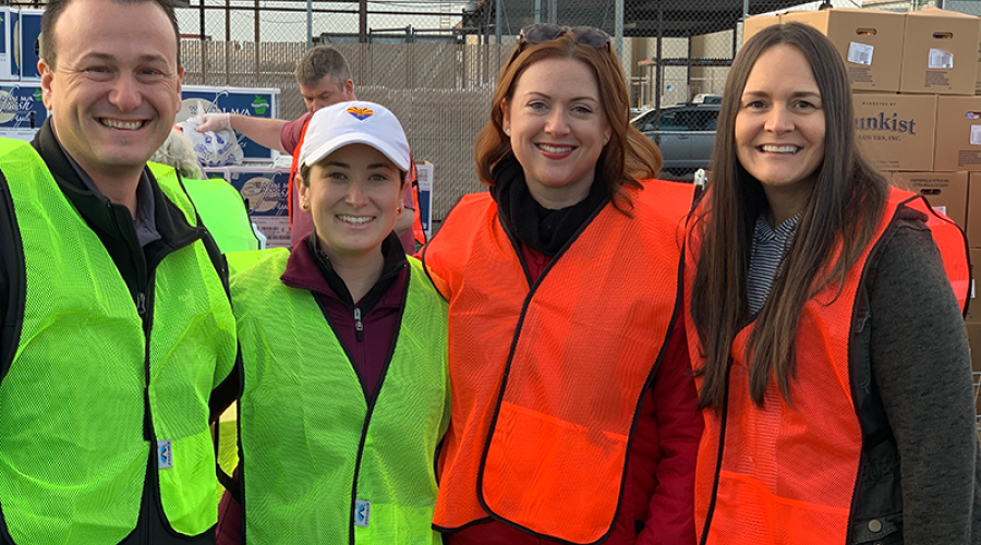 four people wearing neon green or orange vests pose for a photo