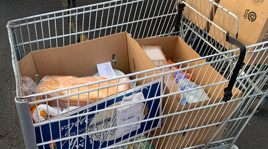 a shopping cart containing two cardboard boxes filled with various food items
