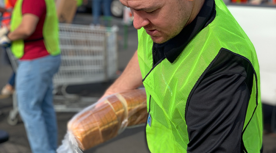 a man wearing a bright green vest is holding a loaf of bread