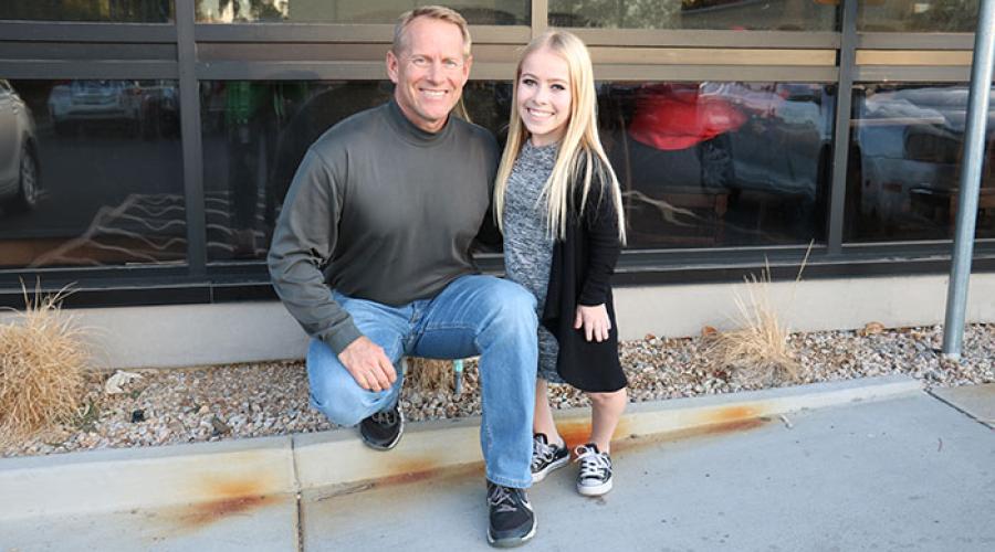 a father and teenage daughter smile at the camera