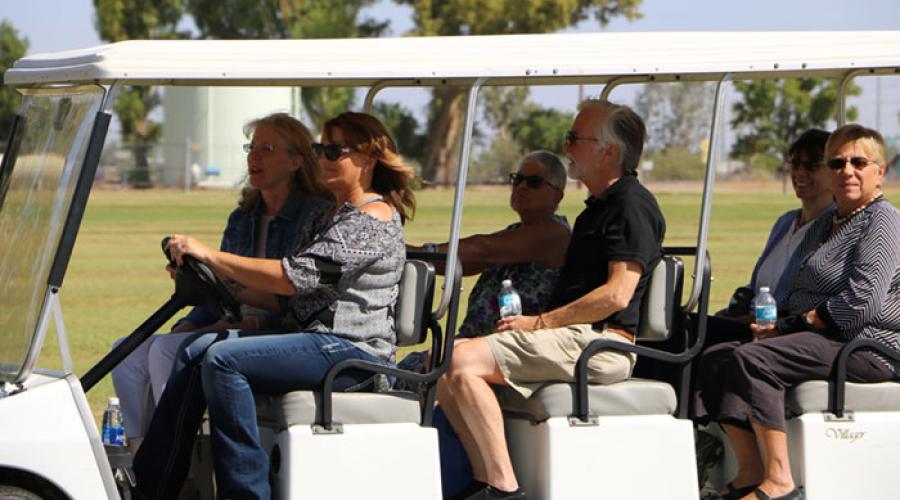 A group of men and women traveling in a golf cart