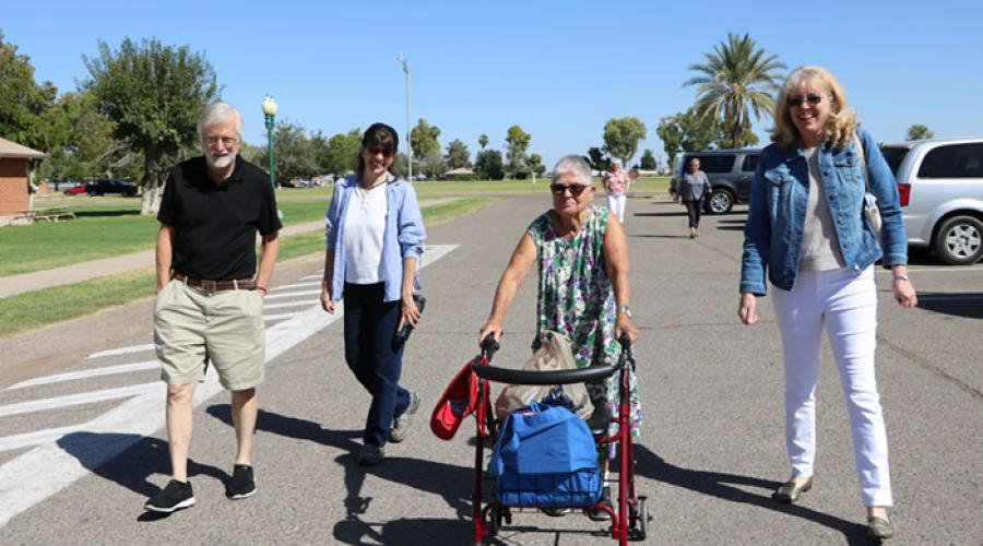 A group of people walking alongside a woman with a walker