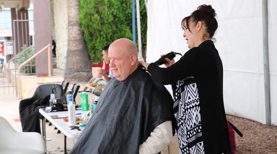 a woman uses an electric razor to give a man a haircut