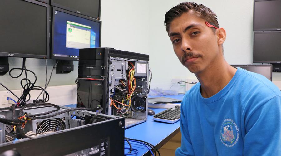 a young man posing in front of dismantled computer hard drives